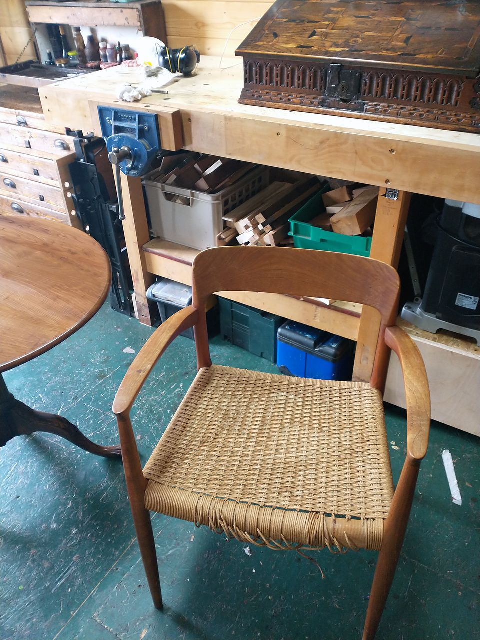 Mid-century armchair with a worn, broken woven paper cord seat, before reweaving