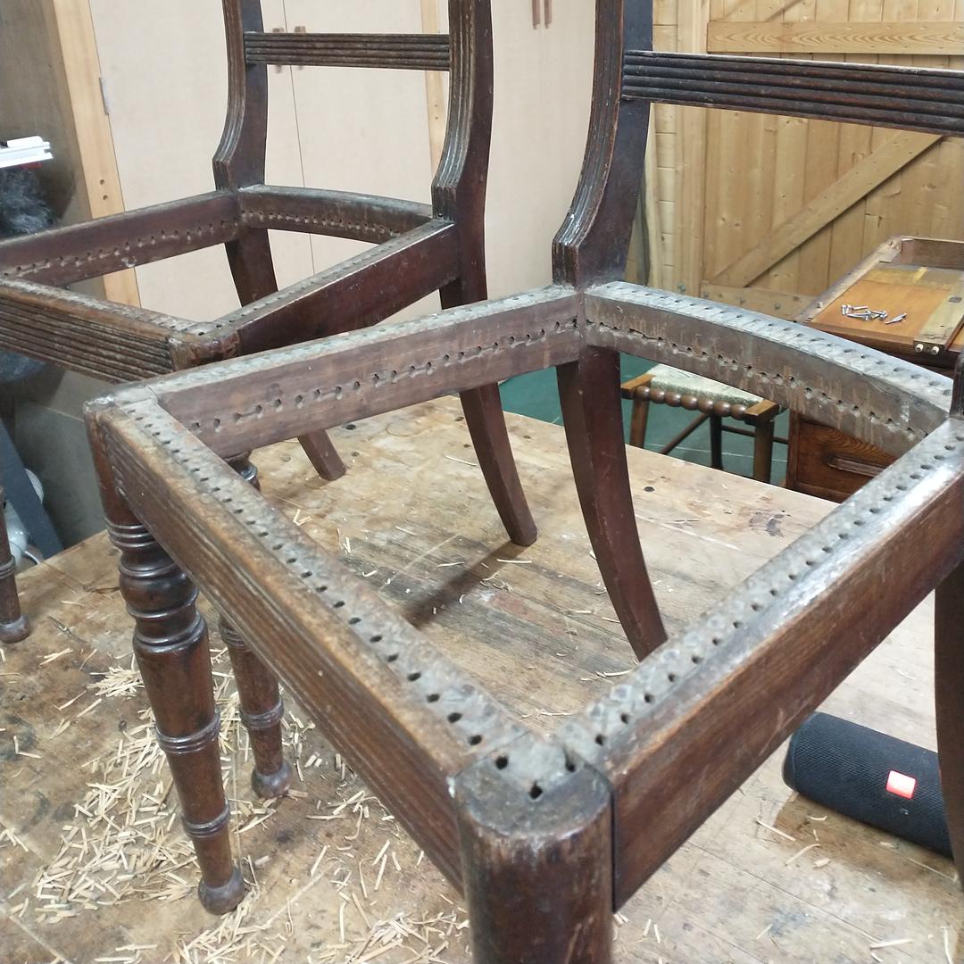 A pair of Regency chair frames with the old cane cut out, showing the row of drilled holes round each seat