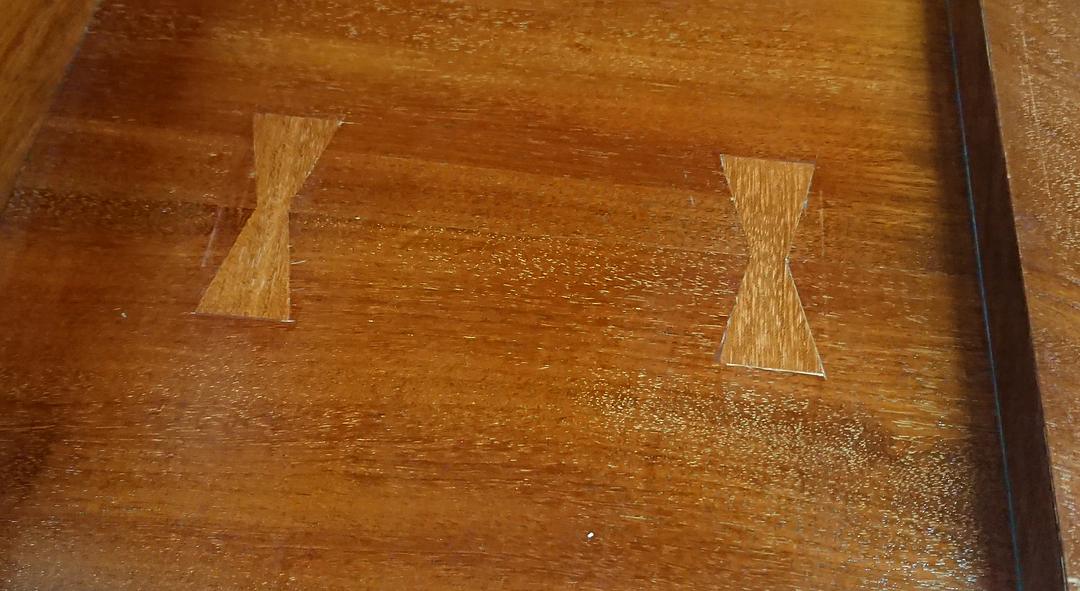 Two inlaid butterfly keys holding a split in a polished wooden top